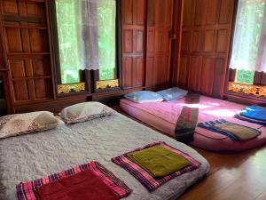 2 camas en una habitación con ventanas en โฮมสเตย์บ้านนายสิงโตเขาคูหา, en Ban Khu Ha Nai (1)