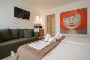 a living room with a couch and a painting of a woman at 23 Hotel Mykonos in Mikonos
