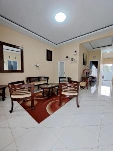 a living room with tables and chairs and a rug at Guguak Puro Guest House in Padangpanjang