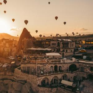 a group of hot air balloons flying over a city at Şah Saray Cave Suites Halal Hotel in Göreme