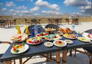 a table with food on it with a view of theramids at Venus Pyramids Inn Rooftop Access & Free Breakfast in Cairo