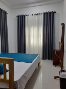 a bedroom with a bed with blue sheets and curtains at VILLA GREEN VILLAGE in Kamburugamuwa