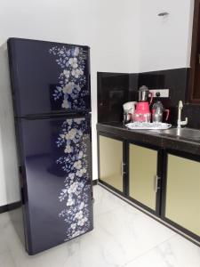 a black refrigerator with flowers on it in a kitchen at VILLA GREEN VILLAGE in Kamburugamuwa