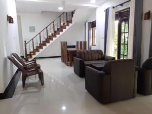 a living room with a couch and chairs and a staircase at VILLA GREEN VILLAGE in Kamburugamuwa