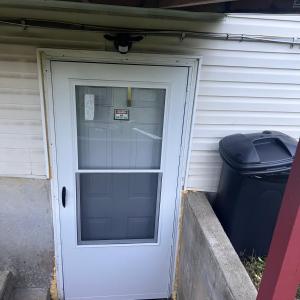 a white door with a window next to a trash can at The McNeil Mansions in Harrisburg