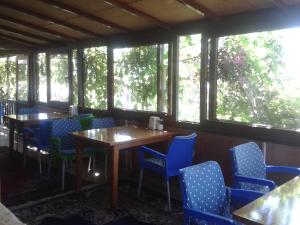 ein Esszimmer mit blauen Stühlen, Tischen und Fenstern in der Unterkunft Cennet Pansiyon in Kaleucagız