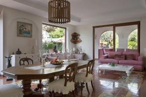 een woonkamer met een tafel en een roze bank bij Villa Gianturco - Luxury In The Green Island in Ischia