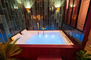 una bañera de hidromasaje en una habitación con una pared de azulejos en Suite jacuzzi, chic romantique climatisé à 50 m du metro, en Villeurbanne