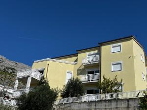 un edificio giallo con balconi bianchi e cielo blu di Kavajin Rooms a Duće