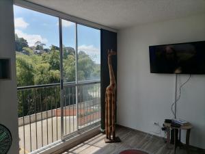 Habitación con ventana grande con una estatua de jirafa en Bonito y central apartamento, en Pereira