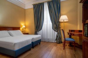 a bedroom with a bed and a desk and a window at Hotel Oceania in Rome