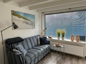 a living room with a couch and a window at ZeeBedStay in Noordwijk aan Zee