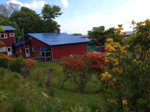 une grange rouge avec un toit bleu dans une cour dans l'établissement NOBORIBETSU no MORI, à Noboribetsu