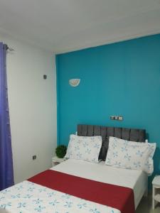 een slaapkamer met een bed met een blauwe muur bij OLD Bonapriso Paisible Appart meublé 2 Chambres in Douala