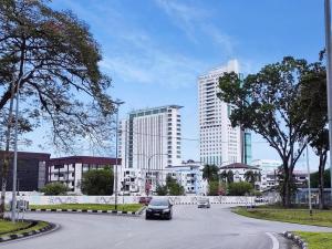 a car driving down a street with tall buildings at Queensway2 Homestay, 4 Rooms 10pax in Sibu