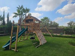 a wooden playground with a slide and a house at Villa familiale aux portes de Marrakech in Marrakesh