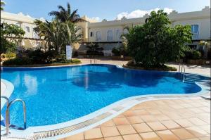 a large blue swimming pool in front of a building at El Sultán 71 Corralejo in Corralejo