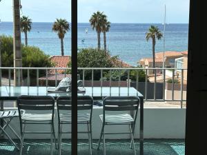 uma mesa e cadeiras numa varanda com o oceano em Appartement vue mer , plage à 50m em Six-Fours-les-Plages