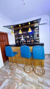 een bar met blauwe stoelen en een bar met wijnflessen bij Cogent Apartments in Uyo