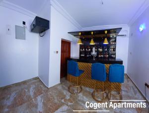 a bar in a room with blue chairs at Cogent Apartments and Hotel in Uyo +3 photos