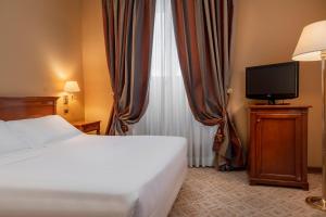 um quarto de hotel com uma cama e uma televisão em Hotel Oceania em Roma