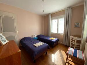 a room with two beds and a table and a window at Maison entre marché et plages de Royan in Royan