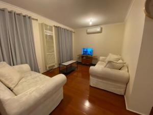 un soggiorno con 2 sedie bianche e una TV di 5 Beds-Whole House-Carrum Beach- Patterson Lake-Fully Furnished a Carrum