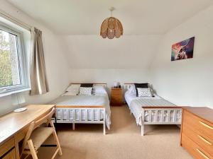 a bedroom with two beds and a desk and a window at Homestead House, Fort Augustus in Fort Augustus