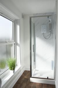 a glass shower in a bathroom with a window at The Whitehouse in Norwich