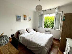um quarto com uma cama branca e uma janela em Maison Familiale Proche Plage, Marché & Commerces - 6 pers. Classée 3 étoiles em La Brée-les-Bains