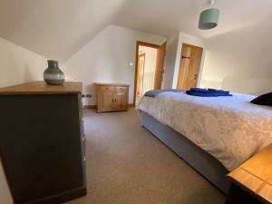 a bedroom with a large bed and a wooden dresser at Mallards Barn on a rural farm in Dingestow