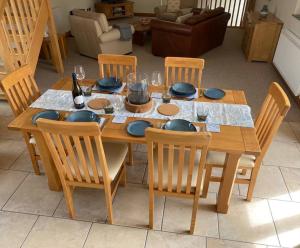 a wooden table with chairs and plates and glasses at Mallards Barn on a rural farm in Dingestow