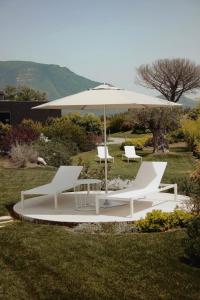 een groep witte stoelen en een paraplu bij Secret Garden Resort & Spa in Palma Campania