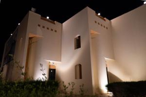 a large white building with lights on it at night at Radwa Ramada Resort in Yanbu