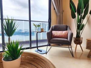 a chair with a pillow in a room with plants at Loft Suite Seaview JB CIQ 7Pax in Johor Bahru