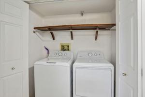 two washing machines in a small white laundry room at Arena De Madeira 502- Premier in St Pete Beach