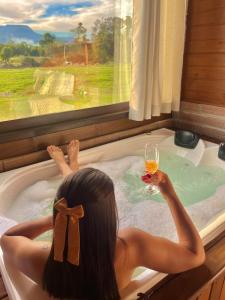 a woman in a bath tub with a glass of wine at Cabanas Vale Verde in Praia Grande