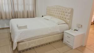 een slaapkamer met een groot wit bed en een nachtkastje bij KK Kiansom Retreat in Kota Kinabalu