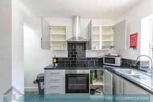 a kitchen with a sink and a stove at Wellfield Serviced Accommodation (Warrington) in Warrington