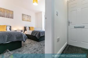 a bedroom with two beds and a door at Wellfield Serviced Accommodation (Warrington) in Warrington