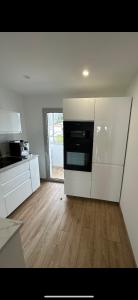 uma cozinha com armários brancos e um micro-ondas preto em Appartement vue mer , plage à 50m em Six-Fours-les-Plages