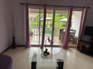 a living room with a glass table in front of a window at Mokara Holiday Apartment in Mahe