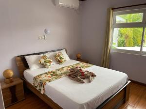 Schlafzimmer mit einem Bett mit weißer Bettwäsche und einem Fenster in der Unterkunft Mokara Holiday Apartment in Mahé