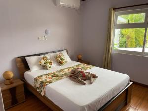 a bedroom with a bed with white sheets and a window at Mokara Holiday Apartment in Mahe