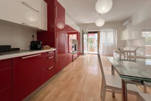 uma cozinha com armários vermelhos e uma mesa de vidro em La Casa di Roma em Roma