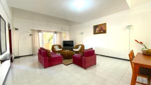 a living room with two red chairs and a table at 2 Bedroom Apartment 250 meters from the Beach in Poste Lafayette