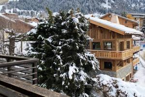een met sneeuw bedekte kerstboom voor een hut bij Bianca appartement proche centre in Megève