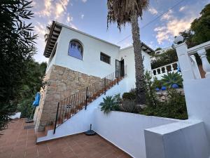 a white house with a staircase and a palm tree at Casa Moya Moraira - Seaview Villa in Teulada