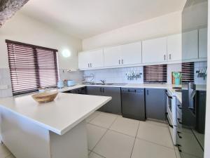 a kitchen with white cabinets and a white counter top at Oceanfront Greek Style Gem in Ballito