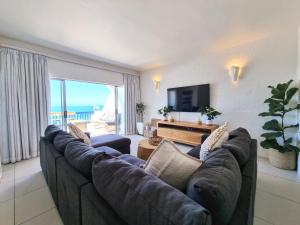 a living room with a large couch and a television at Oceanfront Greek Style Gem in Ballito